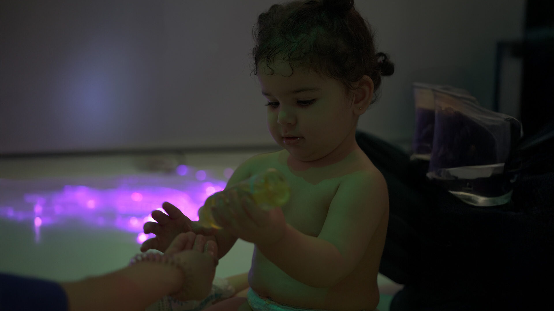 A joyful baby sits on a soft blanket, exploring toys and enjoying a playful moment in a bright room.